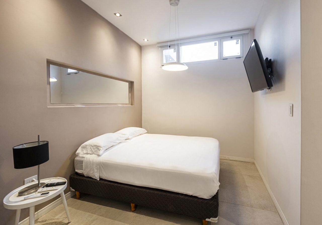 Studio 25 de Mayo - Dormitorio con cama doble, TV y espejo